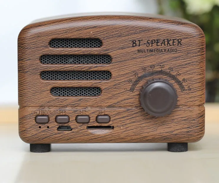 Vintage wood effect portable Bluetooth speaker in pink, black, and wood grain colours on a wooden table.
