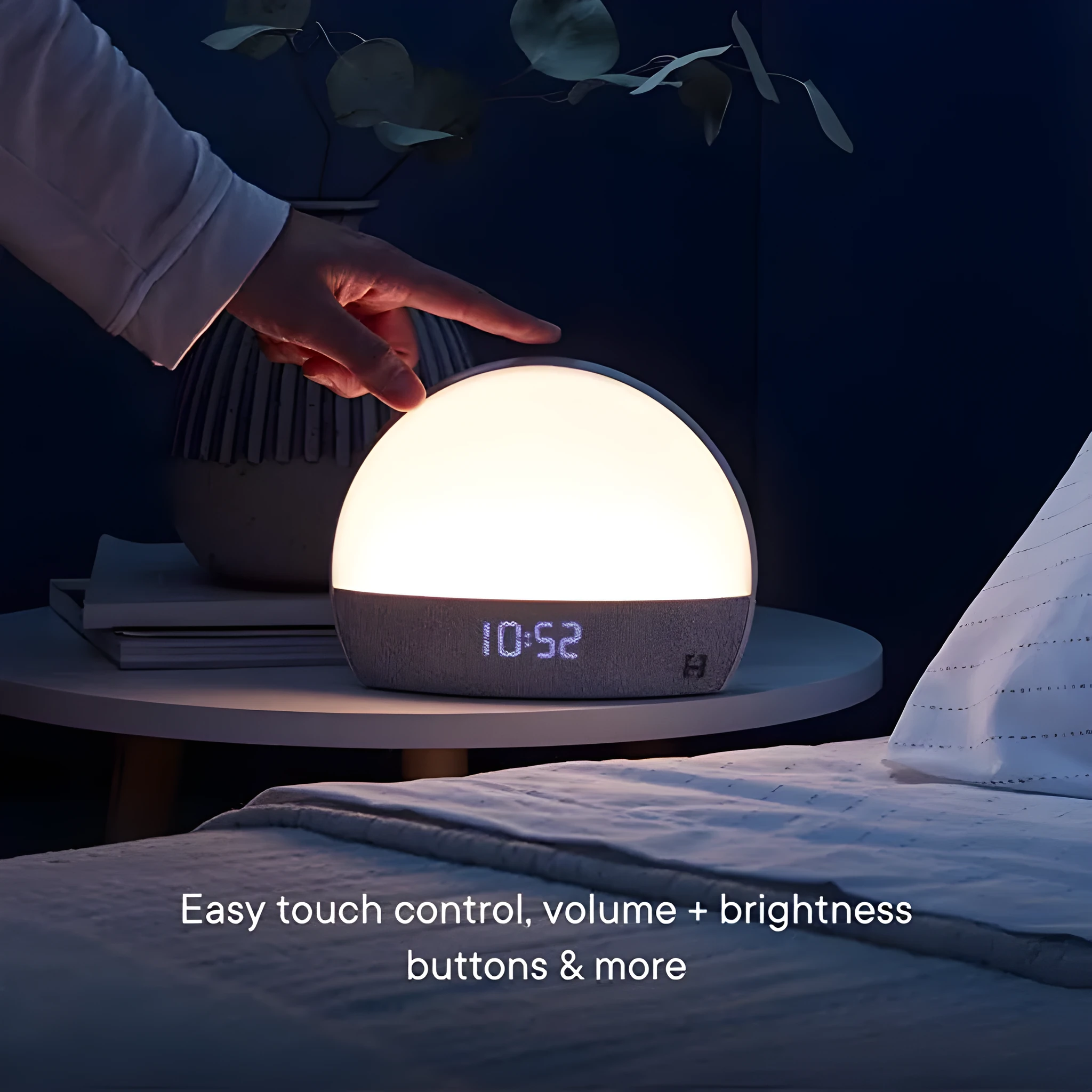 Hatch Restore smart clock in light grey with a night light and white noise machine on a bedside table