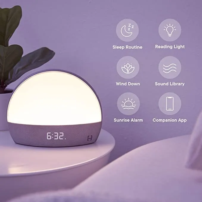 Hatch Restore smart clock in light grey with a night light and white noise machine on a bedside table
