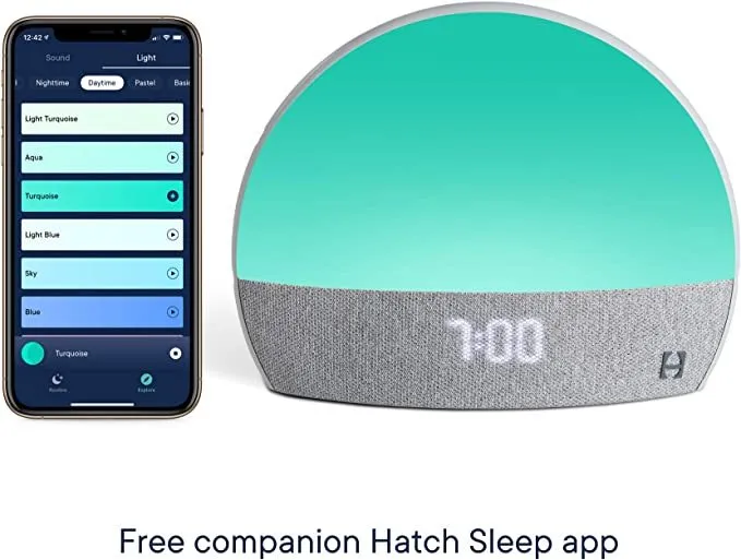Hatch Restore smart clock in light grey with a night light and white noise machine on a bedside table