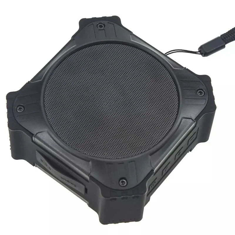 Compact black waterproof Bluetooth speaker with a wrist strap, shown next to a charging cable.
