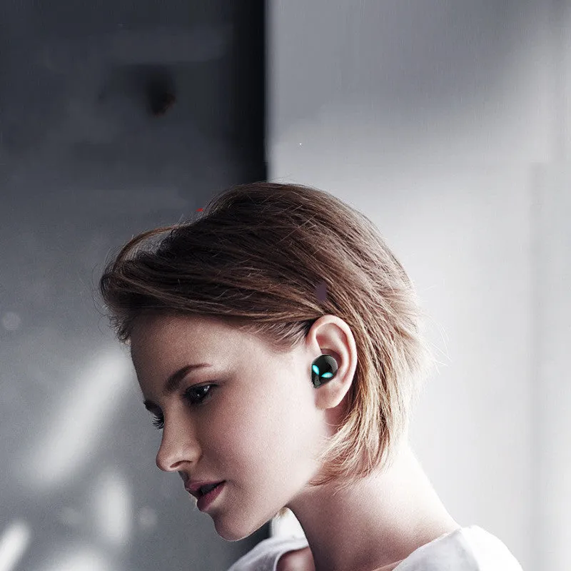 Creative Outer T8 Starman alien-shaped Bluetooth earbuds with LED lights next to their wireless charging case.