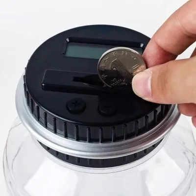 Transparent digital coin counting money box with LCD screen on lid, showing coin slot and clear jar body
