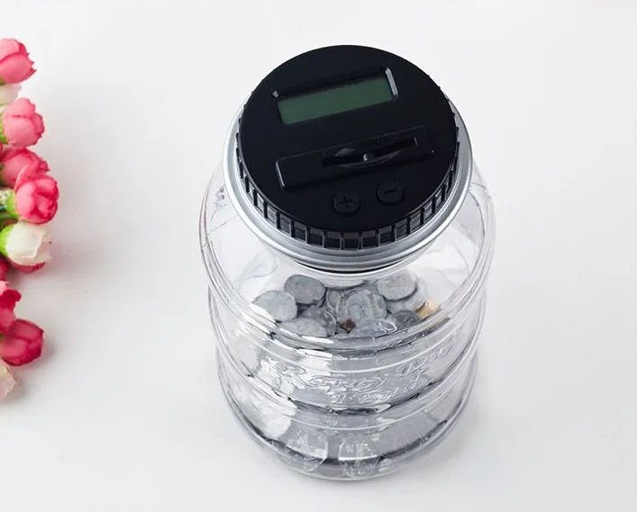 Transparent digital coin counting money box with LCD screen on lid, showing coin slot and clear jar body