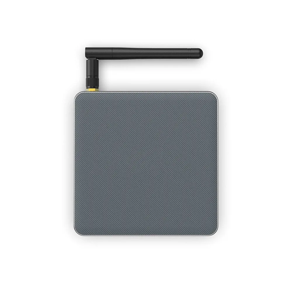 Black Android TV set-top box with HDMI port and remote control on a wooden surface.