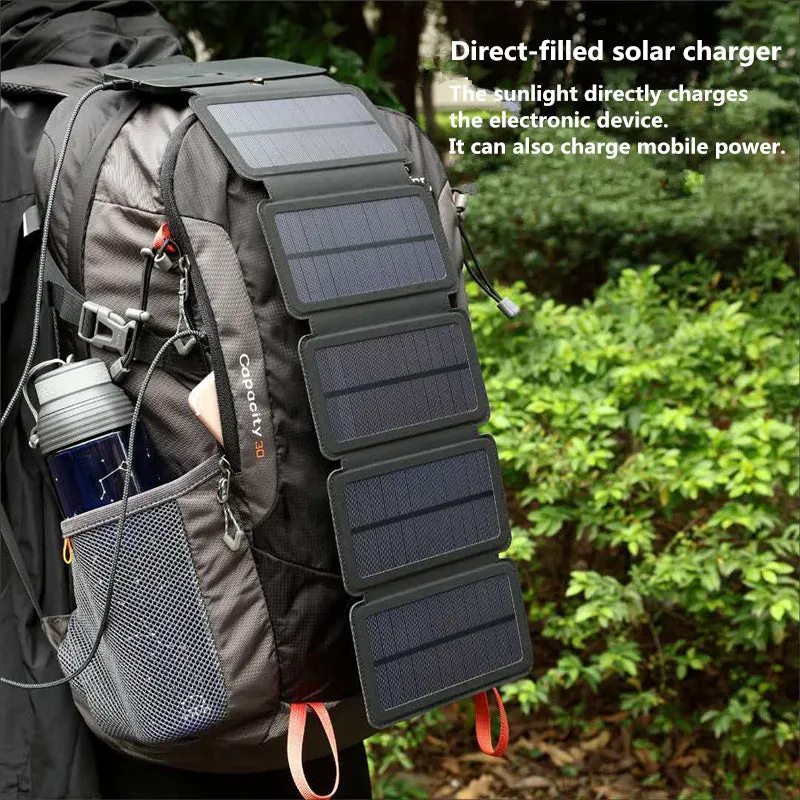 Black folding solar panel charger with monocrystalline cells and USB output, folded flat on a wooden surface, compass buckle visible