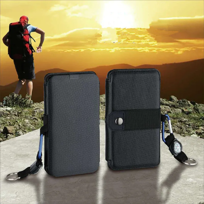 Black folding solar panel charger with monocrystalline cells and USB output, folded flat on a wooden surface, compass buckle visible