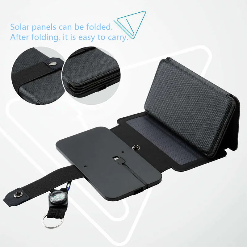 Black folding solar panel charger with monocrystalline cells and USB output, folded flat on a wooden surface, compass buckle visible