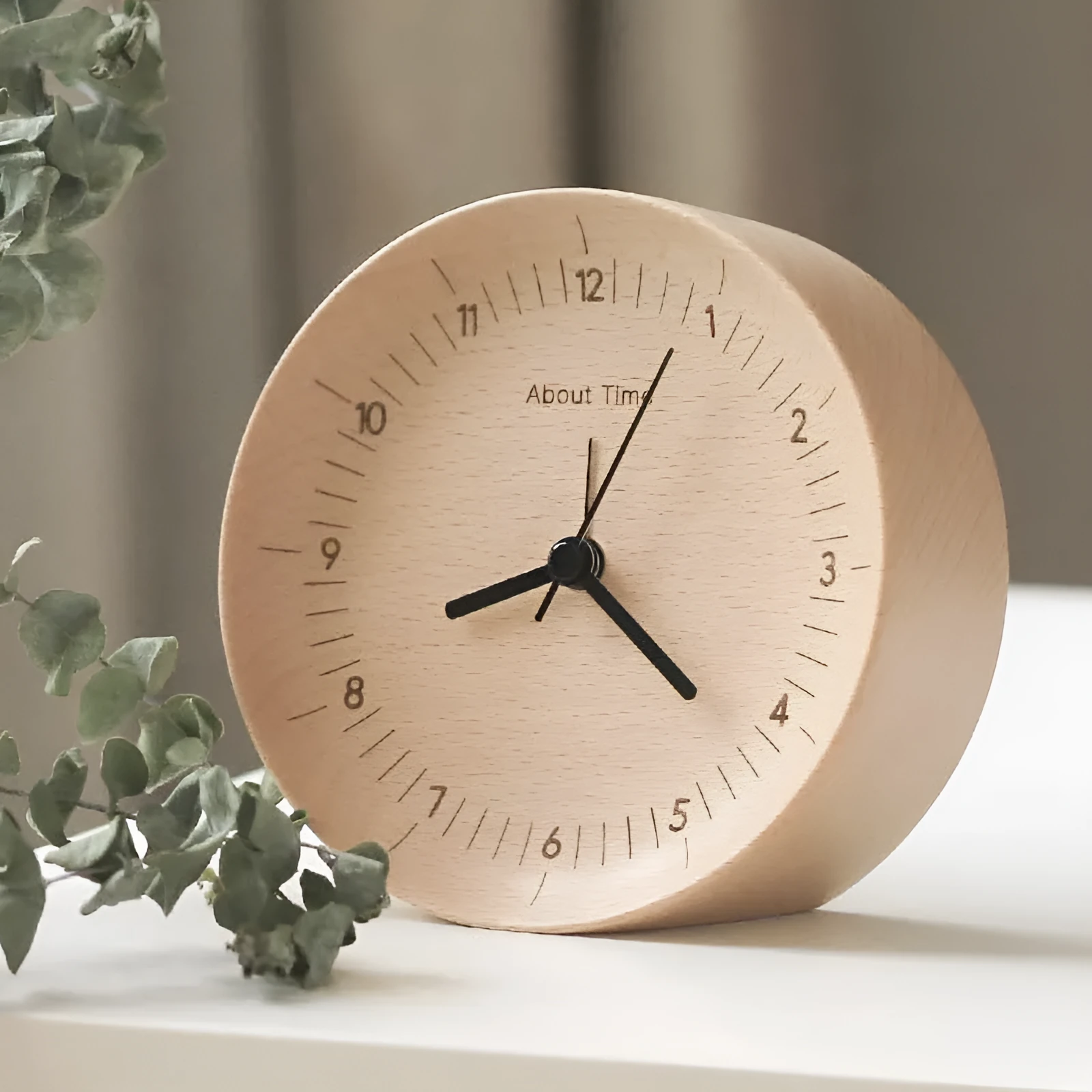 AboutTime log mute pendulum alarm clock in German beech wood, 12cm diameter, featuring Sun brand movement, on a simple desk
