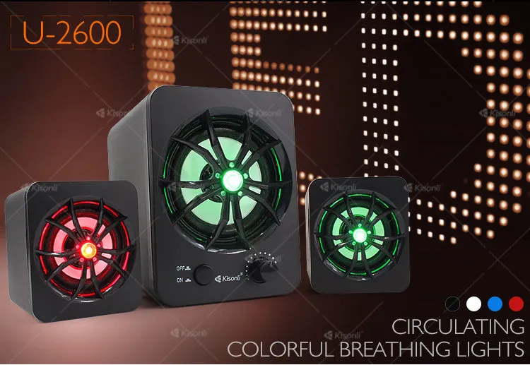 Green 2.1 USB computer speaker with LED lights on a desk next to a laptop.