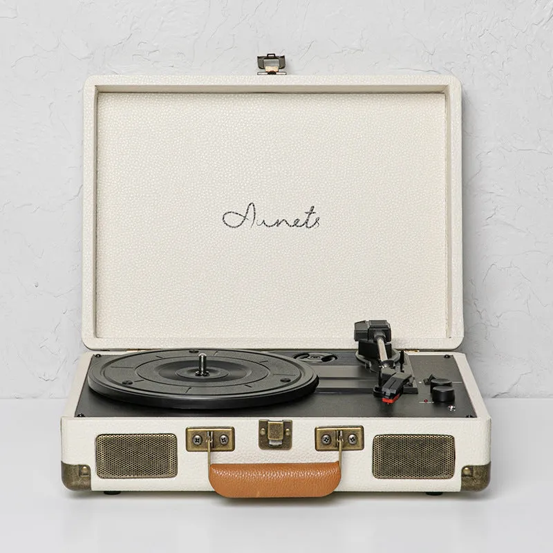 Cream-coloured retro phonograph in leather-effect suitcase with record on turntable and handle visible
