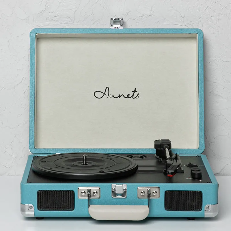 Cream-coloured retro phonograph in leather-effect suitcase with record on turntable and handle visible