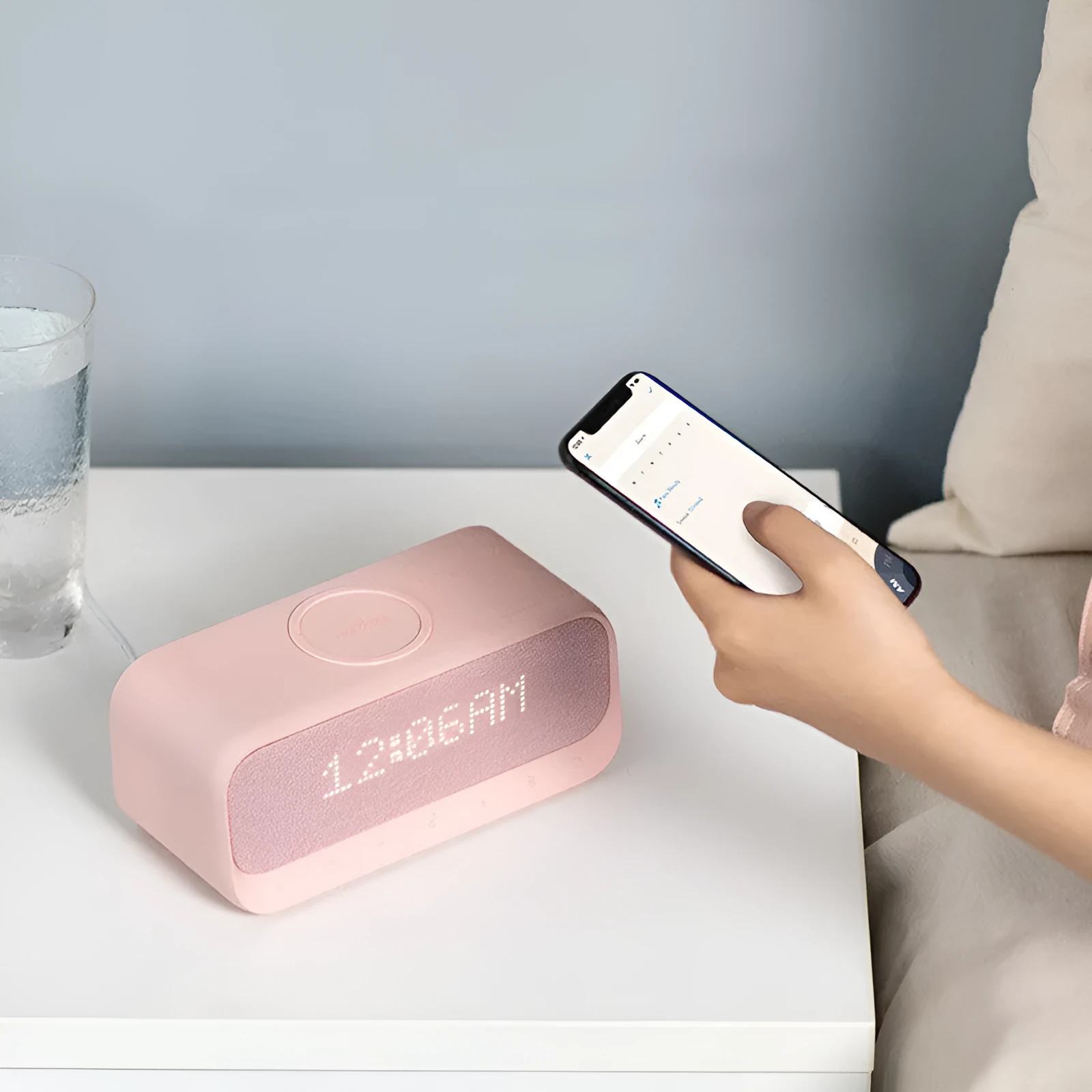 White Anker Soundcore Bluetooth speaker with wireless charging pad and digital clock display