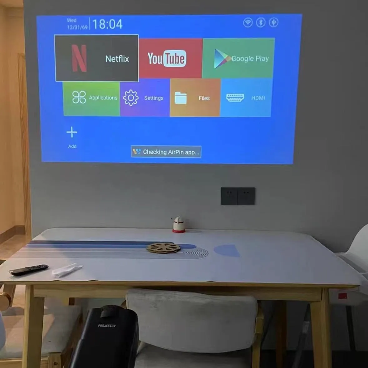 A wireless home gaming projector with a carry handle, showing a 720p HD display on a wall.