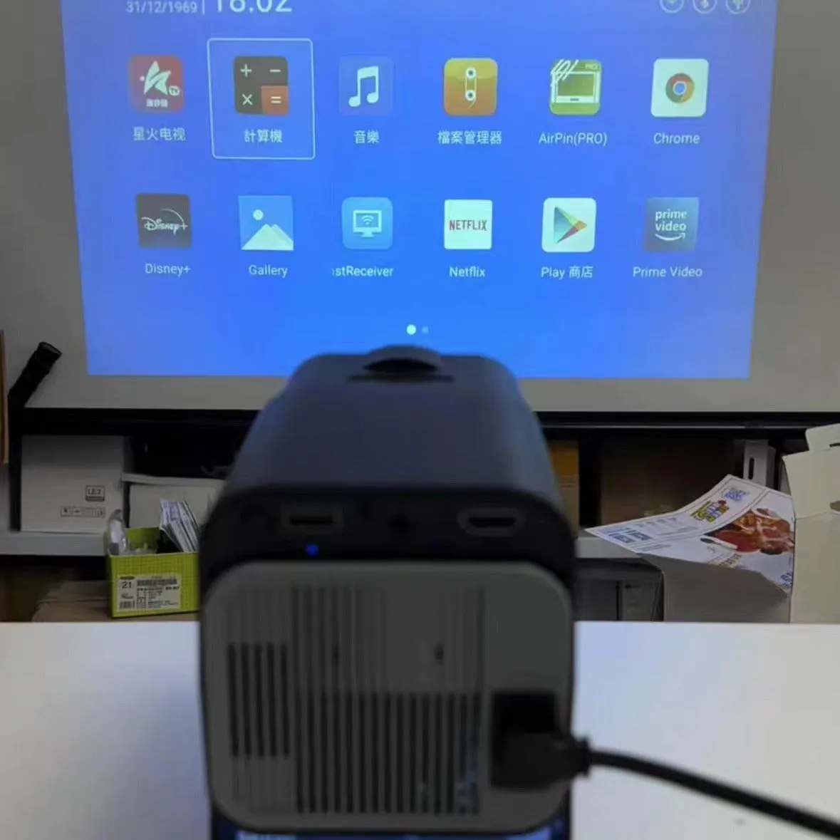 A wireless home gaming projector with a carry handle, showing a 720p HD display on a wall.