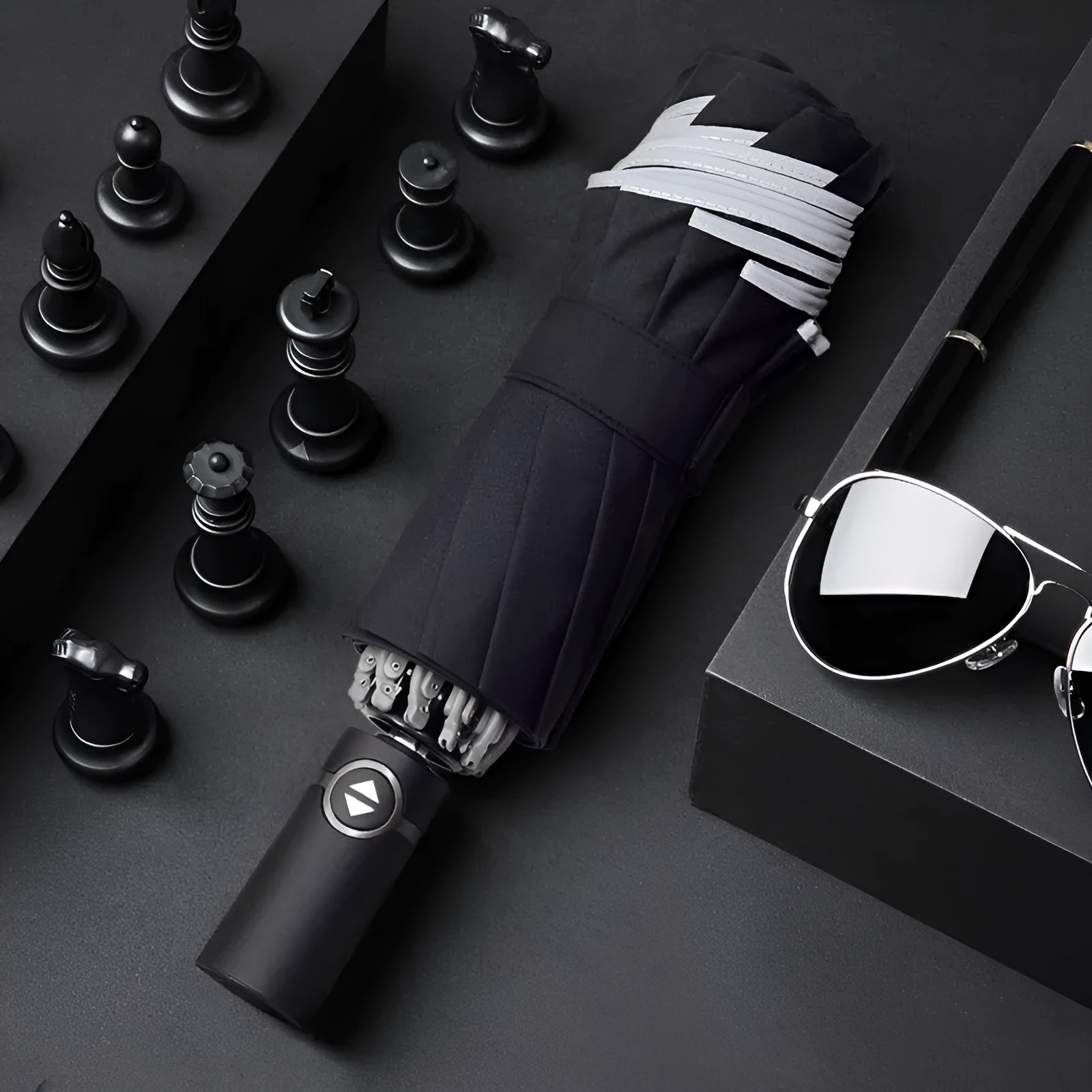Black automatic reverse folding umbrella with plastic handle, shown closed and demonstrating the reverse mechanism.