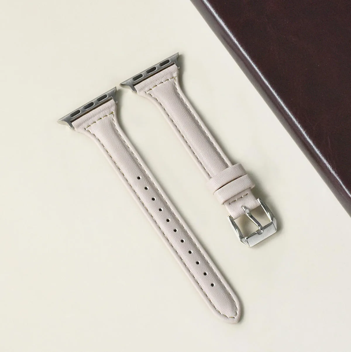 Women's retro slim leather strap for Apple Watch in cream apricot colour on a table