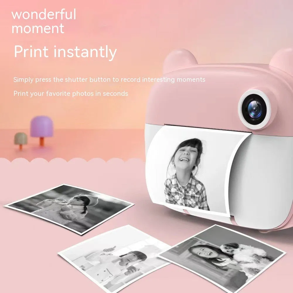 Children's printing camera in pink with dual HD lenses, included crayons and printing paper on white background