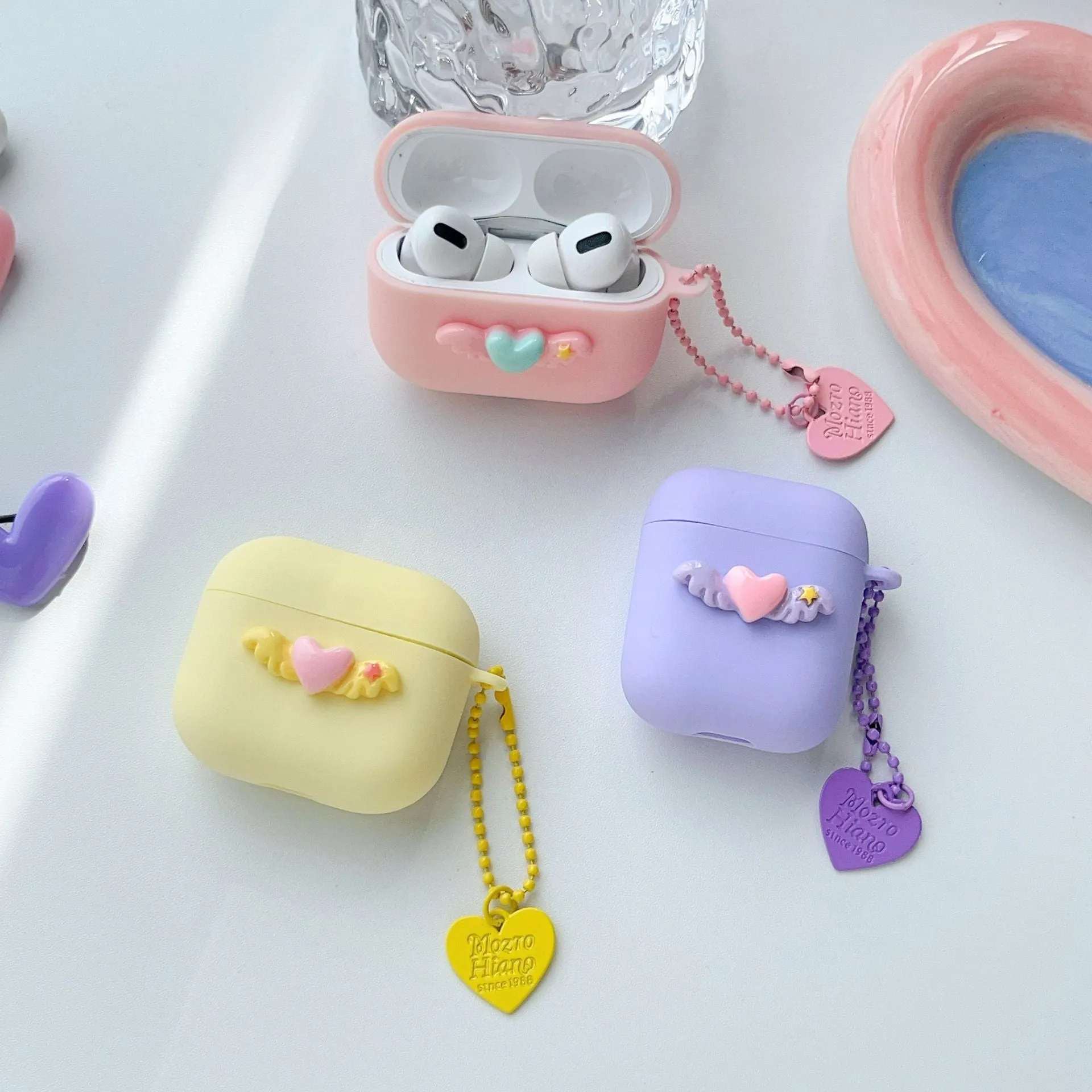 Heart Wings TPU protective case for AirPods with three-dimensional relief design in pink, purple, and yellow colours