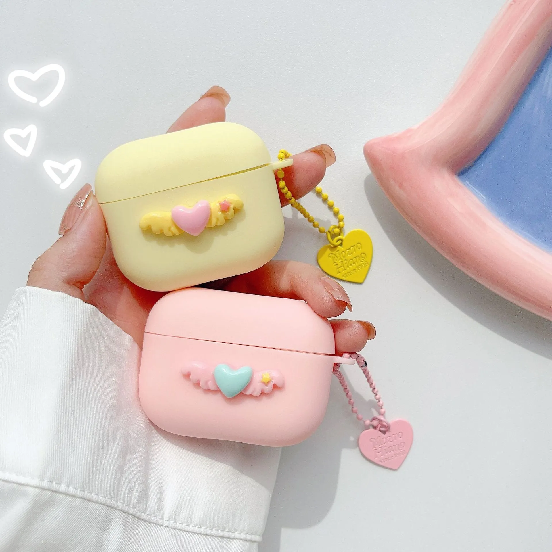 Heart Wings TPU protective case for AirPods with three-dimensional relief design in pink, purple, and yellow colours