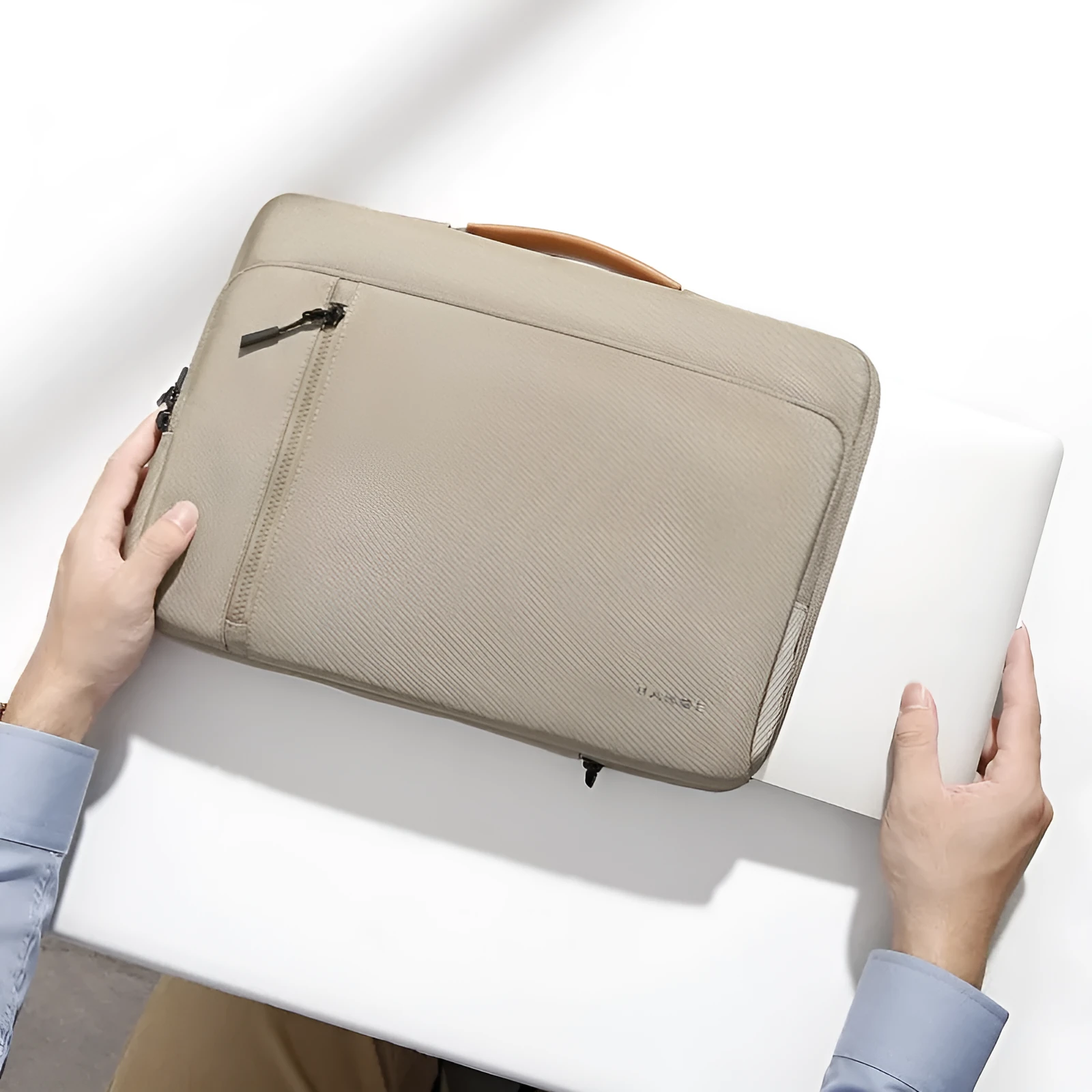 Khaki nylon laptop sleeve with zip closure and visible sewing lines next to a 14-inch notebook