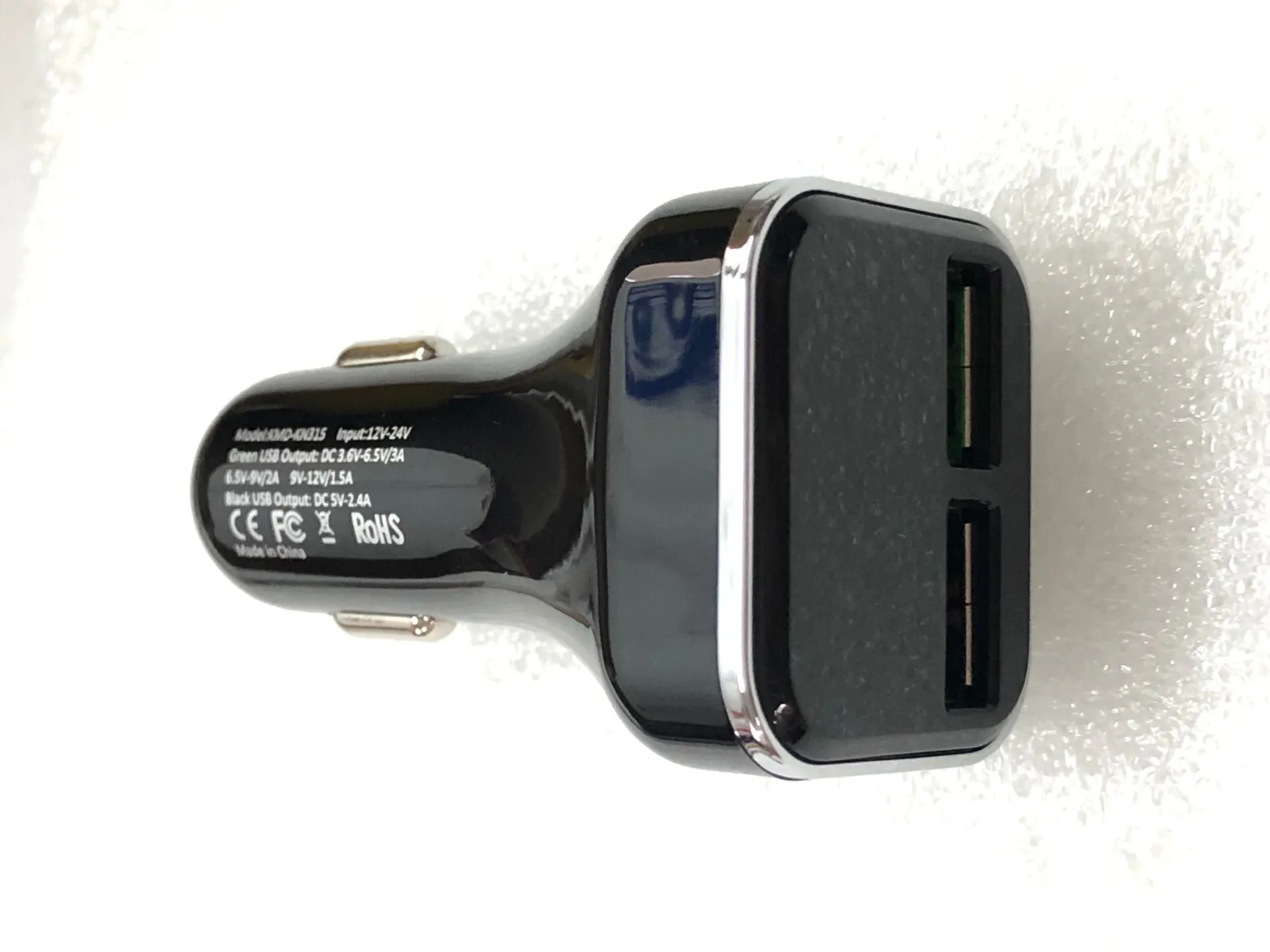 Black dual USB car charger with LCD screen displaying voltage, plugged into a car dashboard socket.
