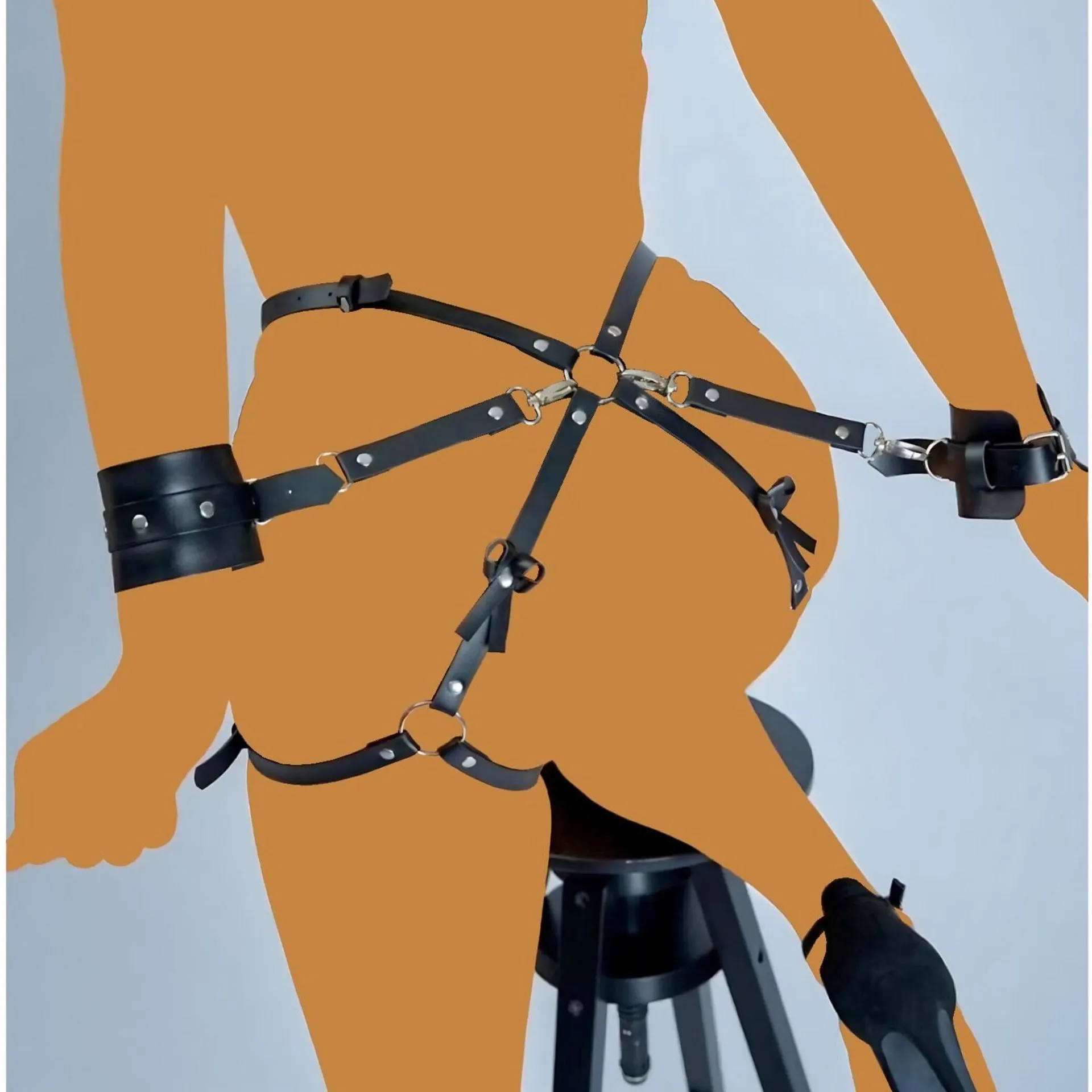 Black leather-look belt with metal buckle and bow detail, handcuffs from same set, on a dark surface