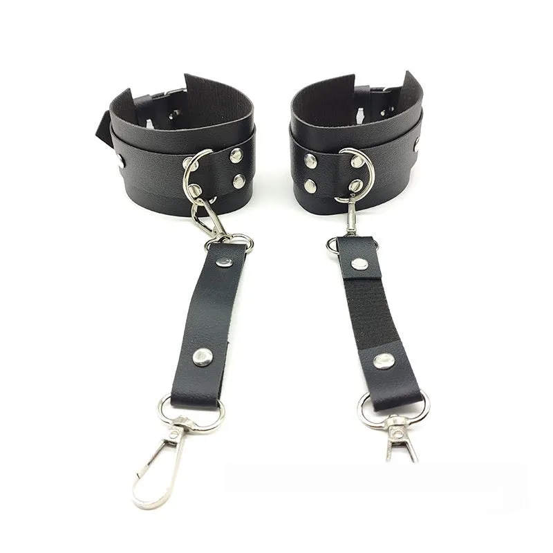 Black leather-look belt with metal buckle and bow detail, handcuffs from same set, on a dark surface
