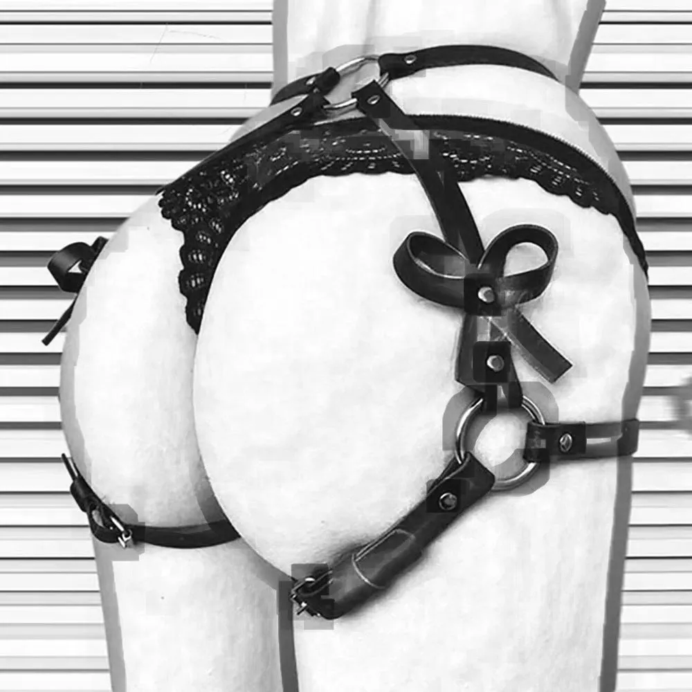Black leather-look belt with metal buckle and bow detail, handcuffs from same set, on a dark surface