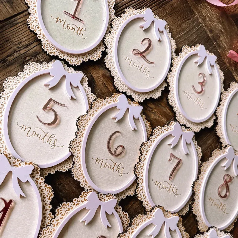 Carved boxwood lace frame bow baby milestone card with ten number stickers on a white background