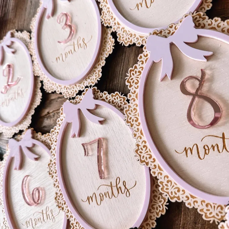 Carved boxwood lace frame bow baby milestone card with ten number stickers on a white background