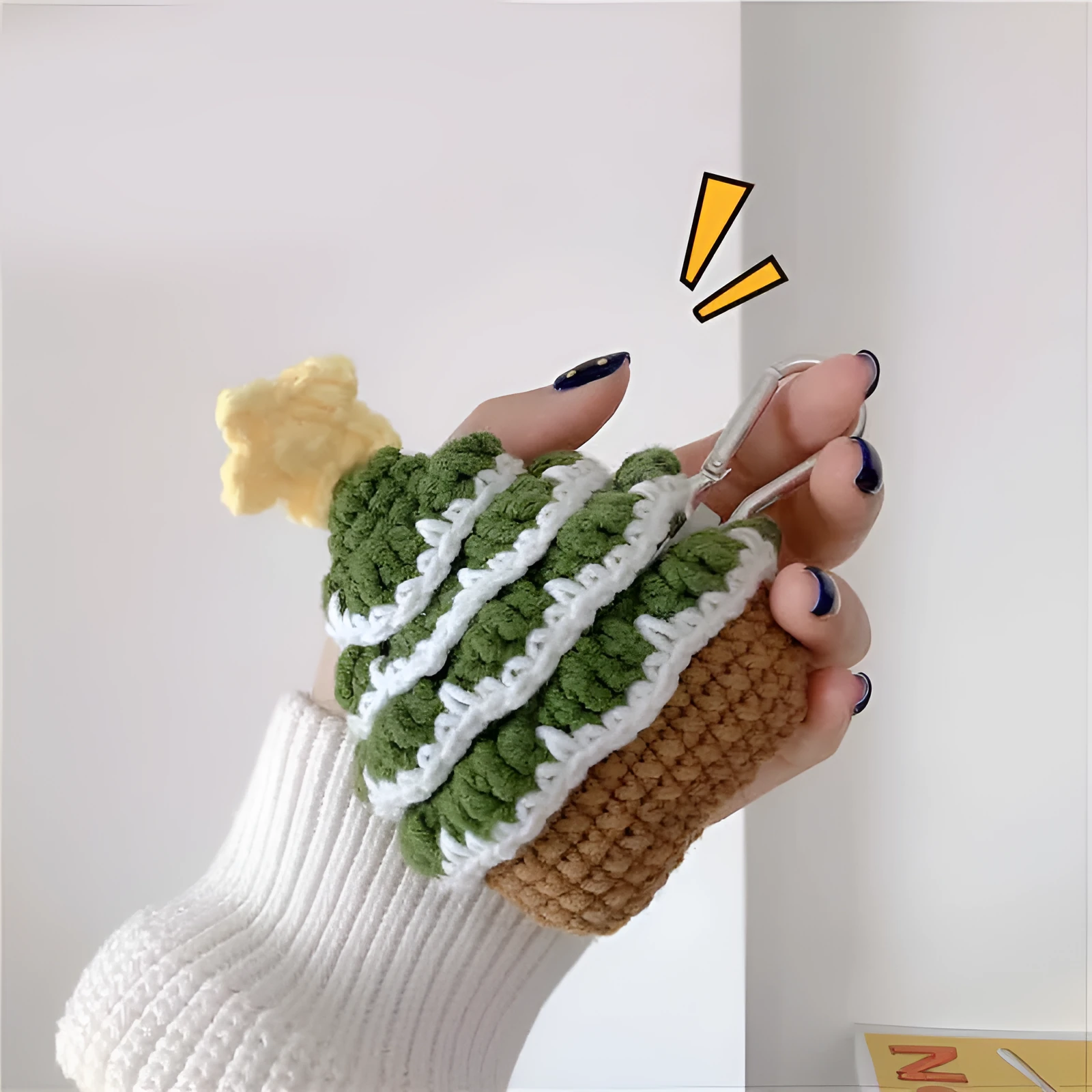 Green knitted Christmas tree flip-style headset case for AirPods with silver hook on white background