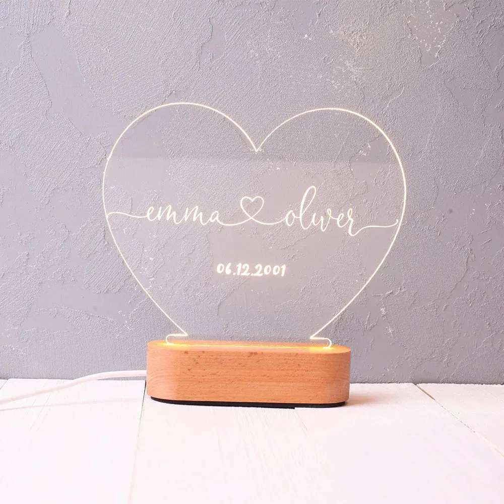 Custom acrylic night light with engraved names and date, lit by LED base.