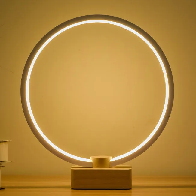 Round small solid wood and bamboo USB-powered LED night lamp on a table.