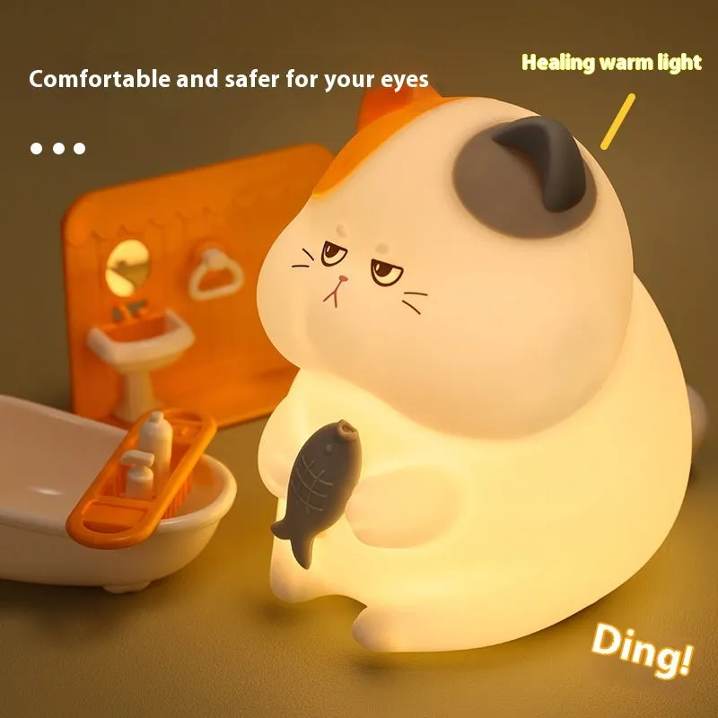Small greedy cat cartoon desktop night light with yellow fin tuna design on a desk.