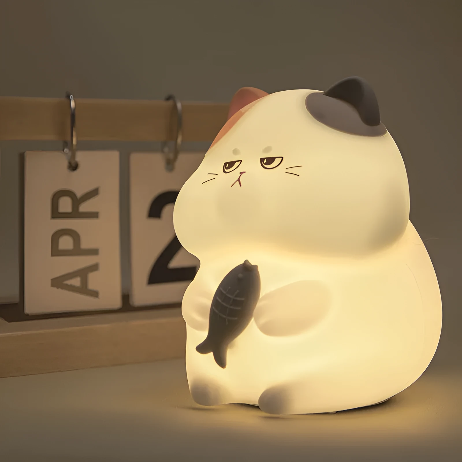 Small greedy cat cartoon desktop night light with yellow fin tuna design on a desk.