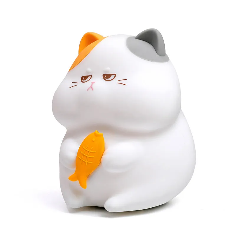 Small greedy cat cartoon desktop night light with yellow fin tuna design on a desk.