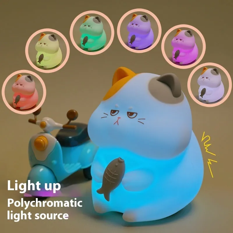 Small greedy cat cartoon desktop night light with yellow fin tuna design on a desk.