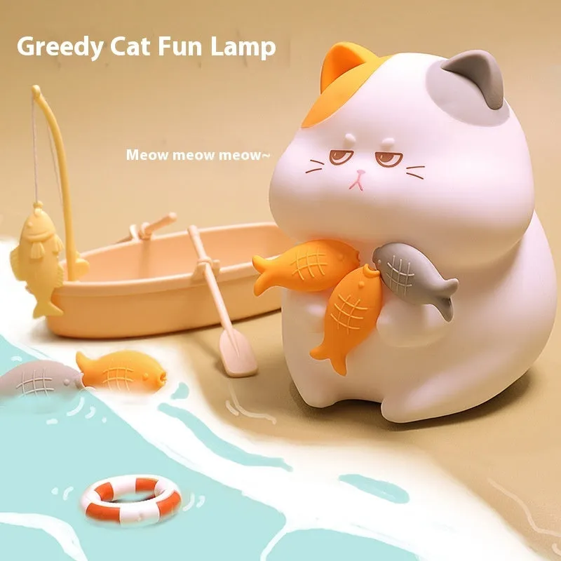 Small greedy cat cartoon desktop night light with yellow fin tuna design on a desk.
