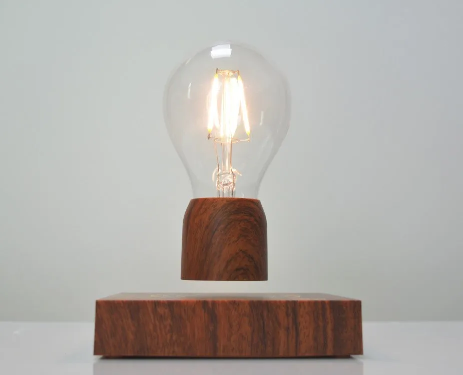 Magnetic levitation desk lamp with floating light bulb on imitation wood base.