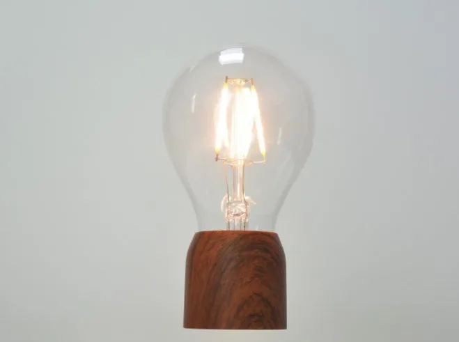 Magnetic levitation desk lamp with floating light bulb on imitation wood base.