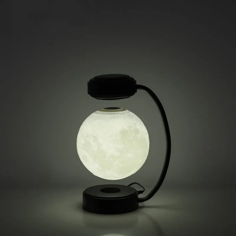 Black magnetic levitation moon lamp floating above base with touch control for bedside use