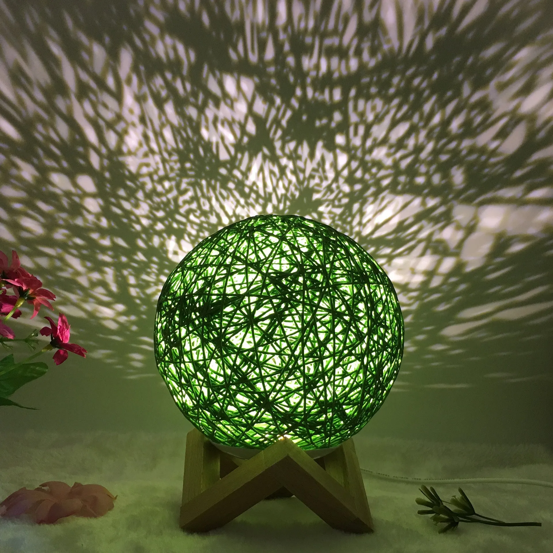 Hand-knit rattan ball table lamp with remote control on a wooden table, powered by USB cable.