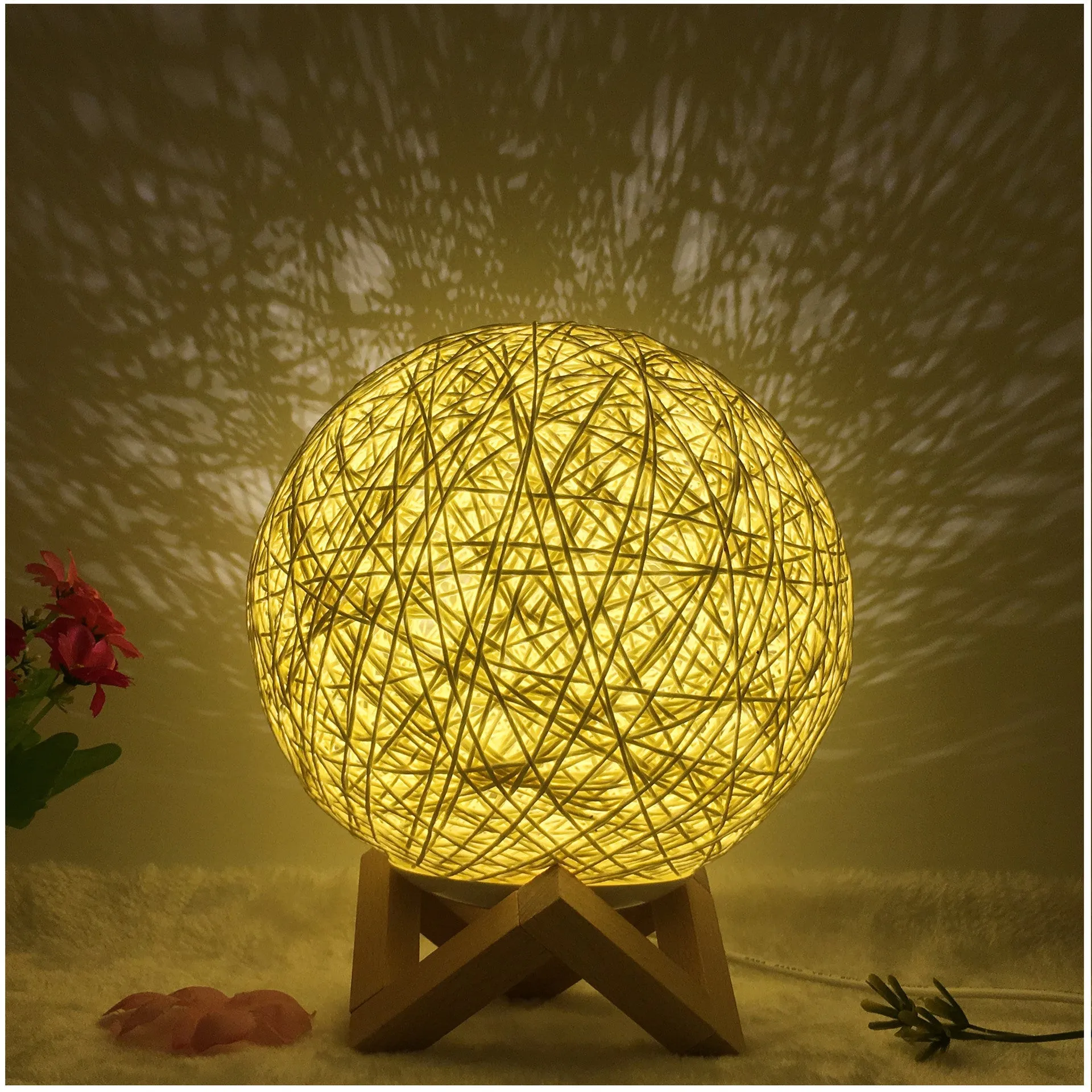 Hand-knit rattan ball table lamp with remote control on a wooden table, powered by USB cable.