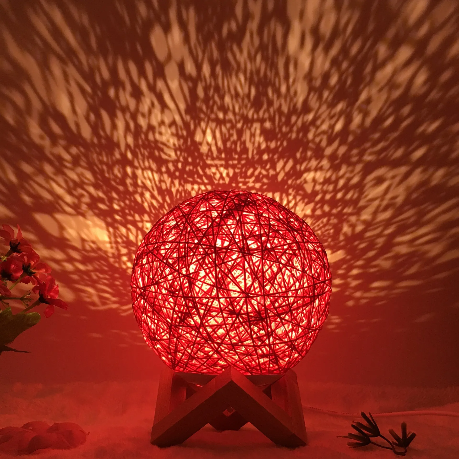 Hand-knit rattan ball table lamp with remote control on a wooden table, powered by USB cable.