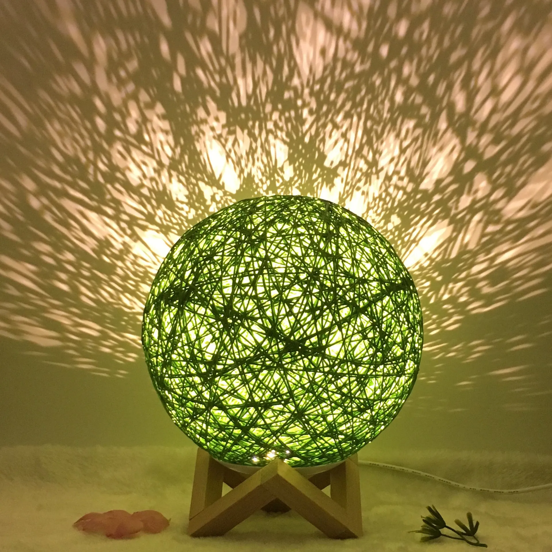 Hand-knit rattan ball table lamp with remote control on a wooden table, powered by USB cable.