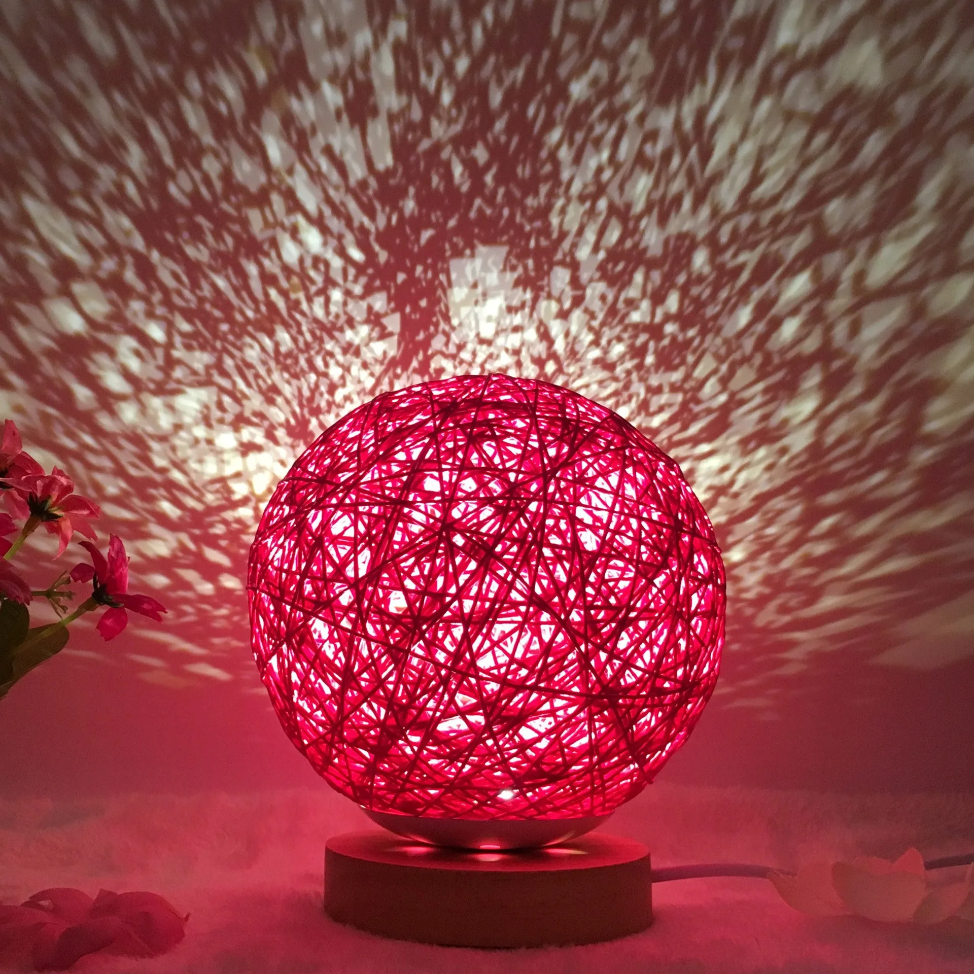 Hand-knit rattan ball table lamp with remote control on a wooden table, powered by USB cable.