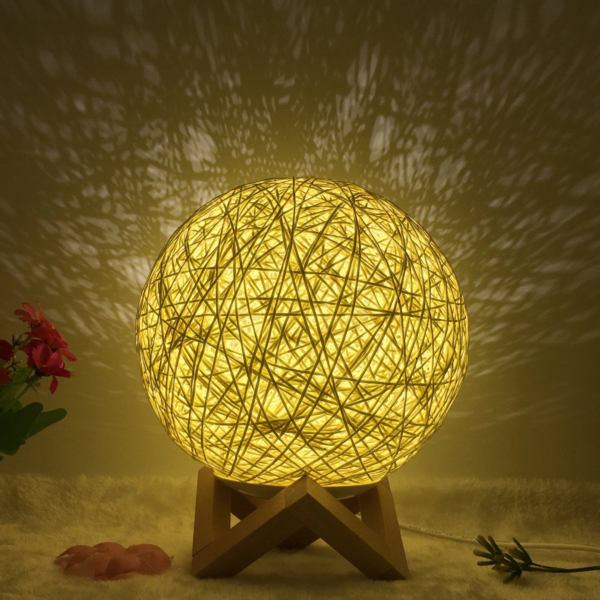 Hand-knit rattan ball table lamp with remote control on a wooden table, powered by USB cable.