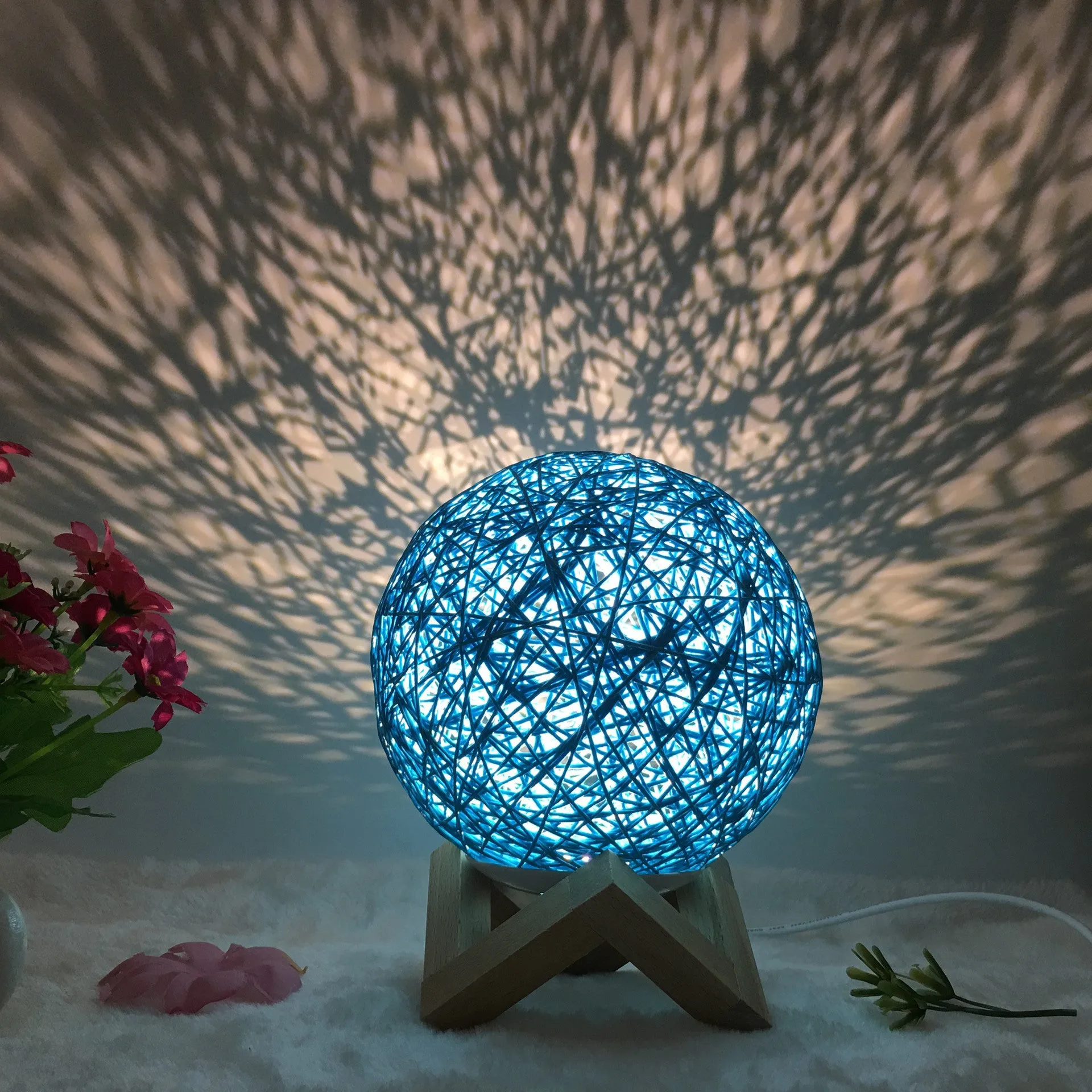 Hand-knit rattan ball table lamp with remote control on a wooden table, powered by USB cable.