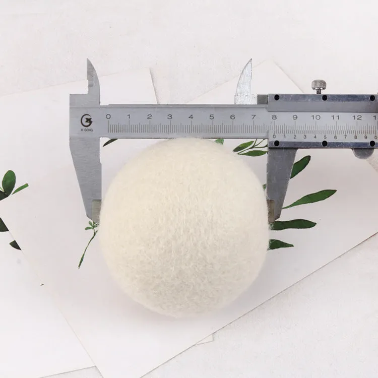 Natural wool laundry drying balls in various sizes next to plain cotton storage bag